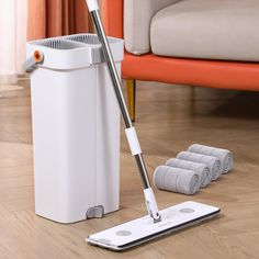 a mop is laying on the floor next to a dustbin and four rolls of toilet paper