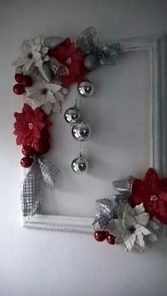 a white frame decorated with red and silver flowers, bells and ornaments hanging from it's sides