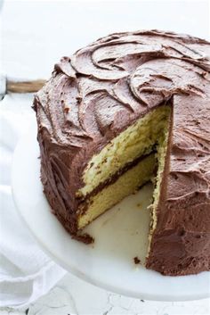 a chocolate cake on a white plate with one slice cut out and ready to be eaten