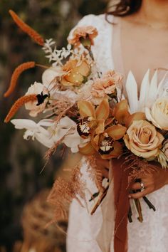 a woman holding a bouquet of flowers in her hands and wearing a white dress with an orange sash