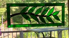 a green stained glass window sitting on top of a wooden deck next to a table