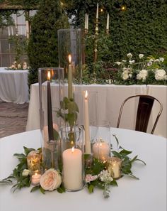 a table with candles and flowers on it in front of some tables set up for an event