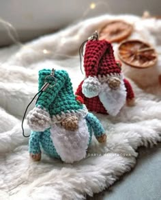 two small crocheted gnomes sitting on top of a white fur covered blanket