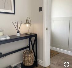 a room with a table, lamp and pictures on the wall above it that is decorated in black and white