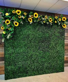 a green wall with sunflowers and greenery in the shape of a baby's name