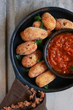 a black bowl filled with fried food next to a brown napkin on top of a wooden table