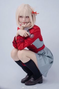 a woman with blonde hair is posing for a photo wearing a red shirt and grey skirt