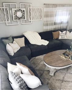 a living room with gray couches and white pillows on the floor, coffee table