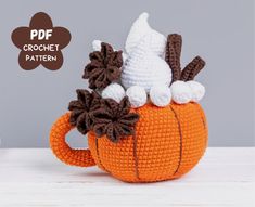 an orange crocheted pumpkin with white and brown decorations