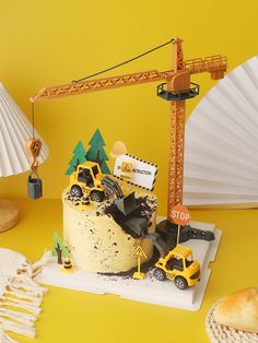 a cake with construction vehicles on it and a paper fan next to it, sitting on a yellow surface