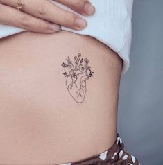 a woman's stomach with a small heart tattoo on the lower belly and flowers growing out of it