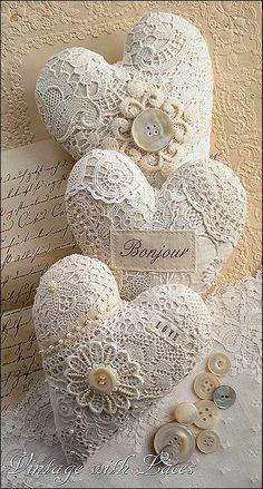 two white teddy bears sitting next to each other on top of a lace covered table cloth