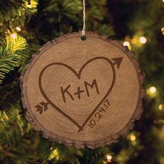 a wooden ornament hanging from a christmas tree with an arrow and heart on it