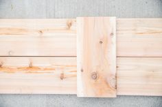 two pieces of wood sitting on top of each other in front of a cement floor