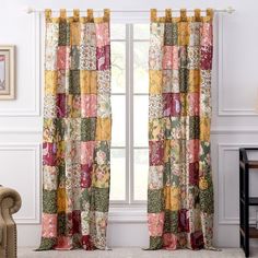 a living room with a chair and window covered in patchwork curtains, along with a painting on the wall