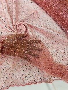 a pair of brown gloves sitting on top of a pink and white cloth covered in sequins