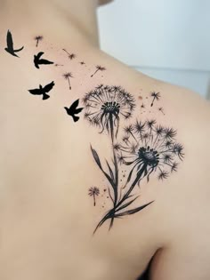 the back of a woman's shoulder with a dandelion tattoo