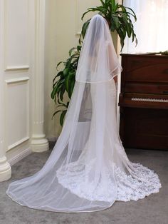 a bride's veil is draped over her wedding dress in front of a piano