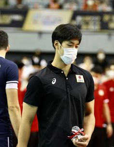 a man wearing a face mask while standing next to another man in a black shirt