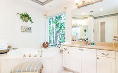 a bathroom with a large bathtub next to a sink and a window in it