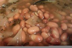 beans and onions cooking in a pot with a spoon