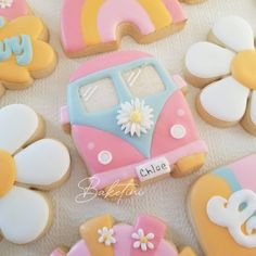 decorated cookies in the shape of vw bus and flowers on a white tablecloth