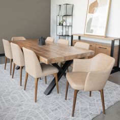 a dining room table with beige chairs and a white rug on the floor in front of it