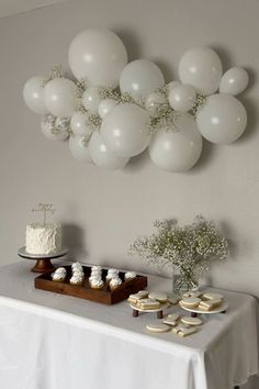 a table topped with white balloons and cupcakes