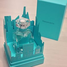 a bottle of perfume sitting on top of a blue box next to a green box