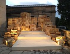 several stacks of wooden pallets sitting on top of a stone walkway next to a building