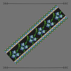 a beaded bracelet with blue flowers and green leaves on the side, along with an arrow