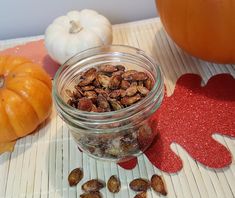 a glass jar filled with nuts sitting on top of a table next to pumpkins