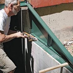 an older man is working on the side of a building with tools in his hands