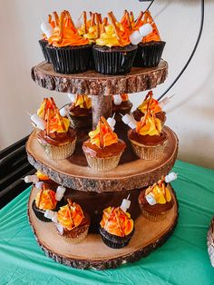 a three tiered cake with cupcakes and orange decorations on it's sides