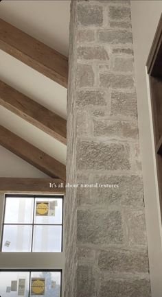 a tall brick pillar in the middle of a room next to a window with wood beams