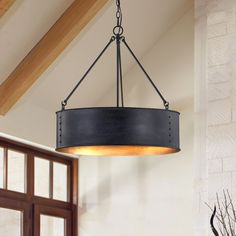 a light fixture hanging from the ceiling in a room with wooden beams and windows on both sides