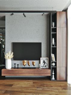 a living room with wooden floors and a large tv on the wall, surrounded by bookshelves