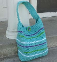 a blue purse sitting on the ground next to a white pole