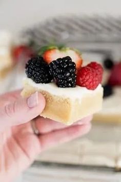 a person holding a piece of bread with fruit on it and raspberries in the middle