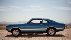 a blue car parked on top of a dirt field