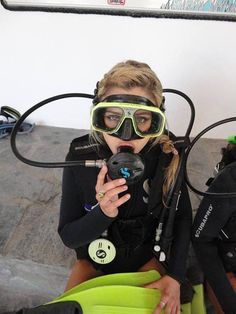 two women wearing scuba gear and goggles are sitting on the ground with their hands together