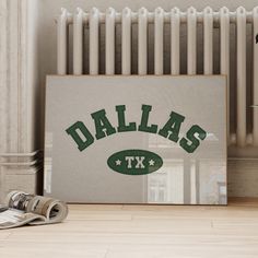 an image of the word dallas texas in green on a canvas next to newspapers and a radiator