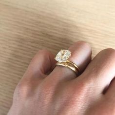 a woman's hand with a yellow diamond ring on her left hand and the other hand holding it