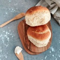 two loaves of bread sitting on top of a wooden plate next to a spoon