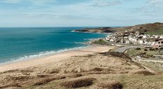 an aerial view of a beach with houses on the shore and ocean in the background