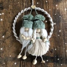 an ornament with two gnomes hanging from it's side on a wooden surface