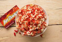 a bowl filled with red and white popcorn next to a candy bar