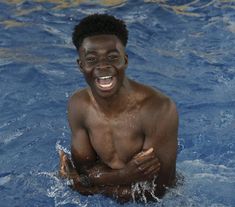 a man in the water is smiling and holding his hands up to his chest as he swims