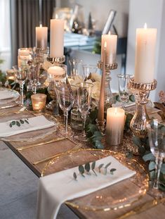 the table is set with candles, plates and napkins for an elegant holiday dinner