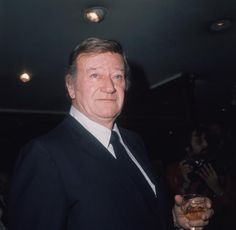 a man in a suit and tie holding a glass with something on his left hand